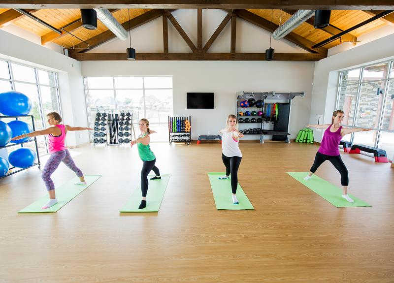 Four Harvest Green residents take a yoga class at the fitness studio.