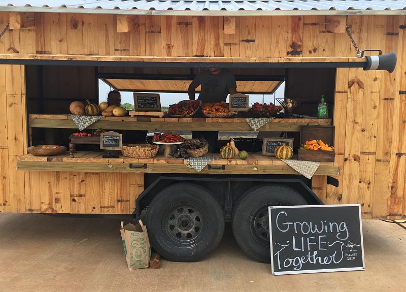 Harvest Green's produce trailer at Farmers Market with sign: Growing Life Together.