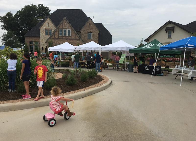 Children and adults enjoy the Harvest Green Farmers Market in Richmond, TX.
