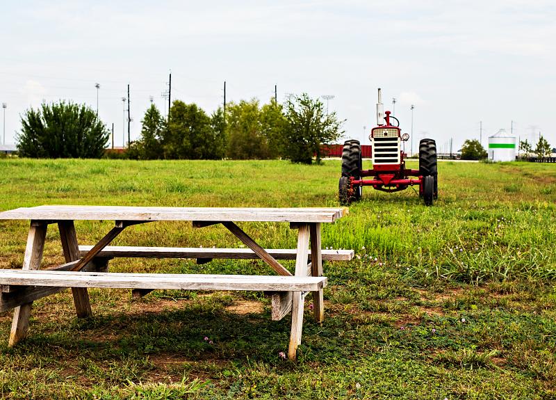 A tractor and picnic bench in field near Harvest Green's Village Farm.