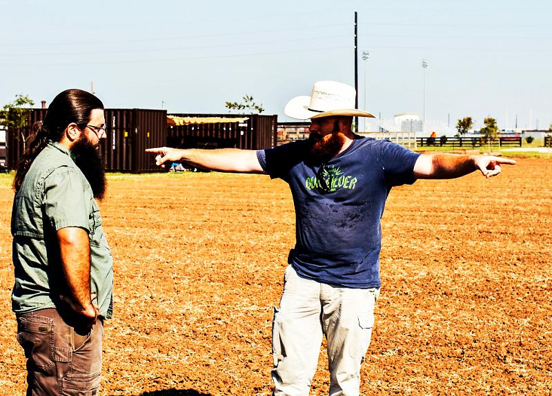 Two men talk in fields of The Village Farm in Fort Bend.