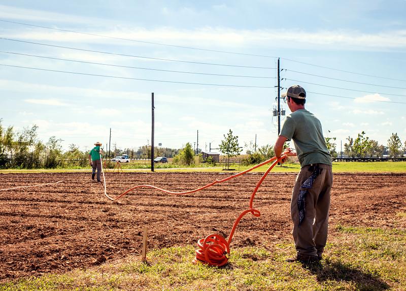 Two people prepare to water the soil at Harvest Green's Village Farm.