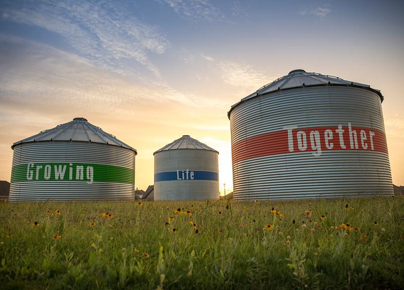 A community photo of Harvest Green's silos which say Growing Life Together.