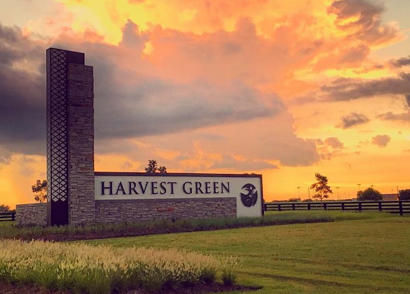 A vivid orange sunset view of Harvest Green's towering community entrance monument.