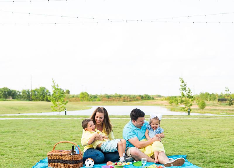 A family four have a picnic on the ground of Harvest Green.