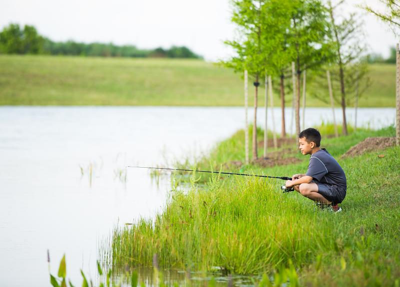 A boy fishing in Fort Bend at one of Harvest Green's lake.
