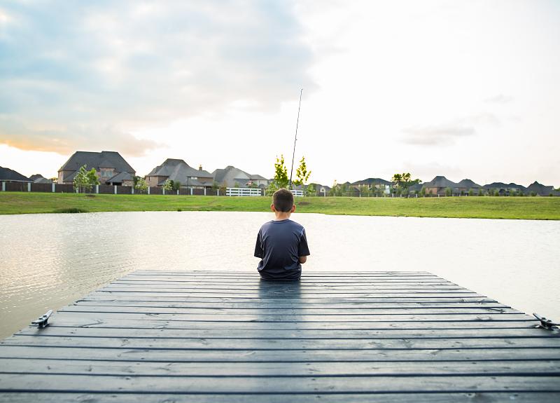 A boy fishing on a dock at one of Harvest Green's lakes.