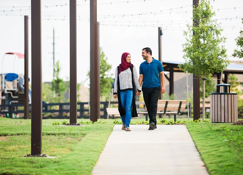 Couple walking a paved trail in the Harvest Green community, Fort Bend.