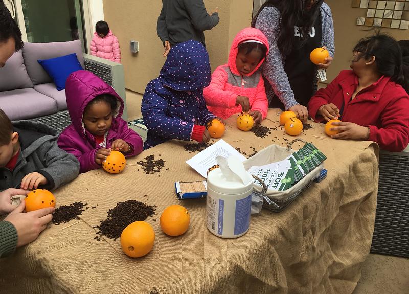 Children craft with oranges and cloves during a Harvest Green resident event.