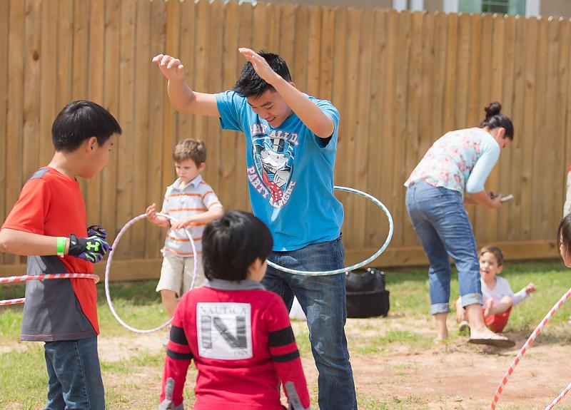 A family plays with hula hoops during a Harvest Green resident event.