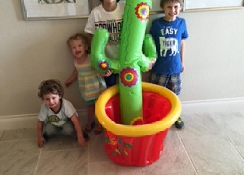Children pose beside an inflatable cactus in a Fort Bend model home.